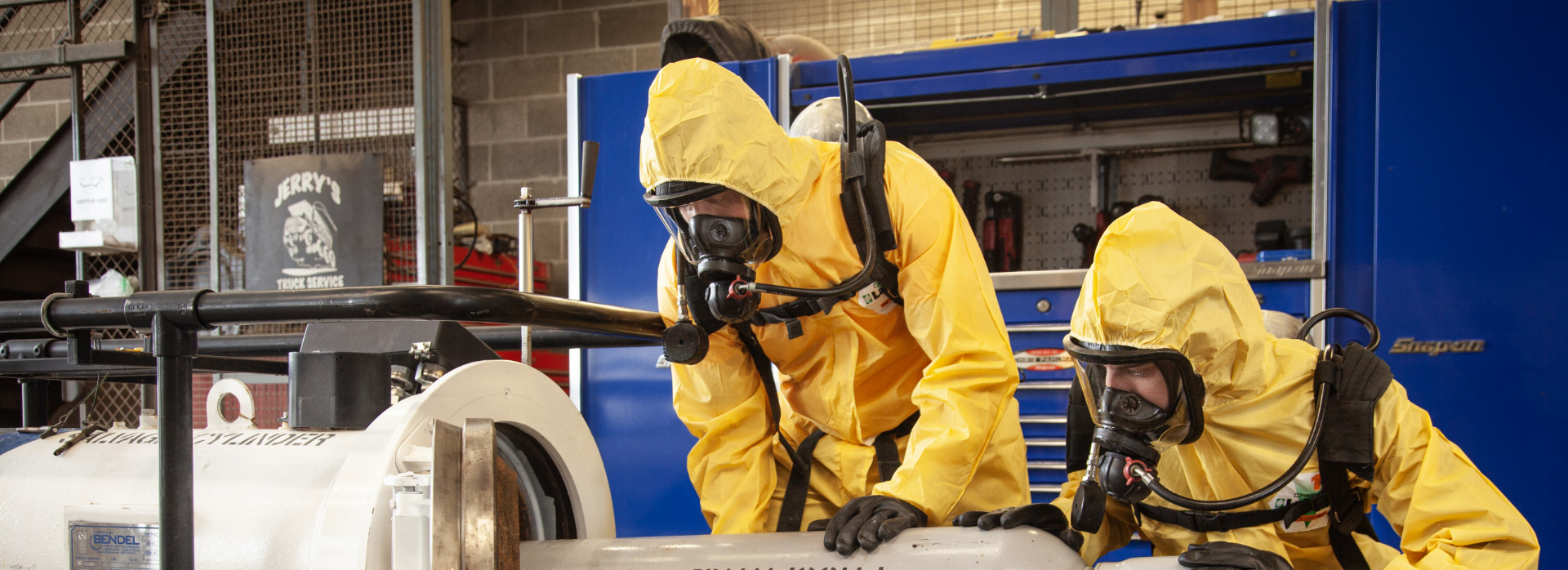 waste management workers in yellow suits and oxygen masks