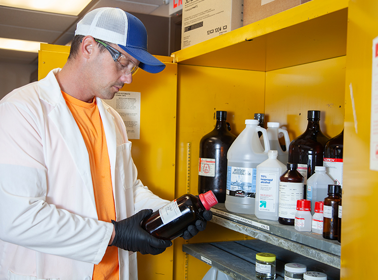 customized waste management worker wearing hat, safety glasses, and white coat