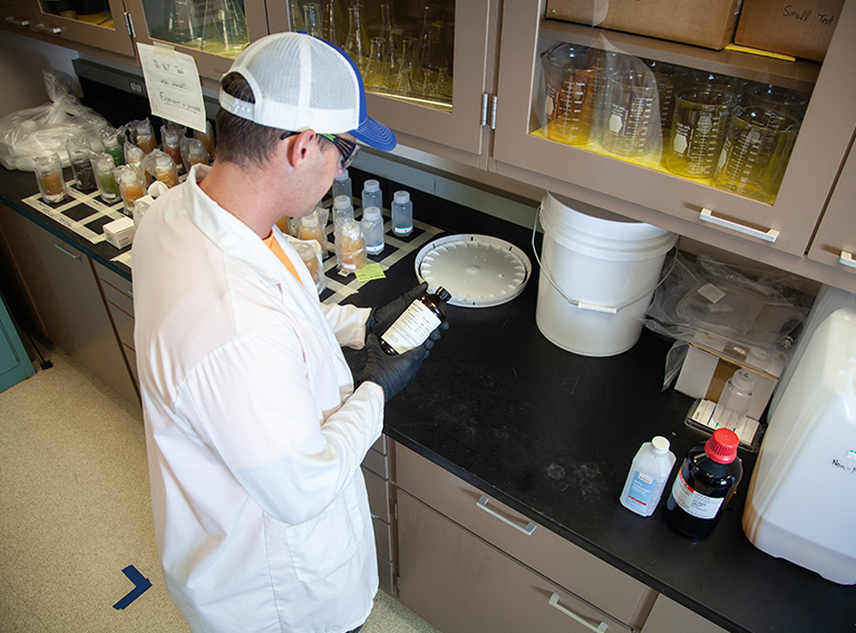 customized waste management worker wearing hat, safety glasses, and white coat