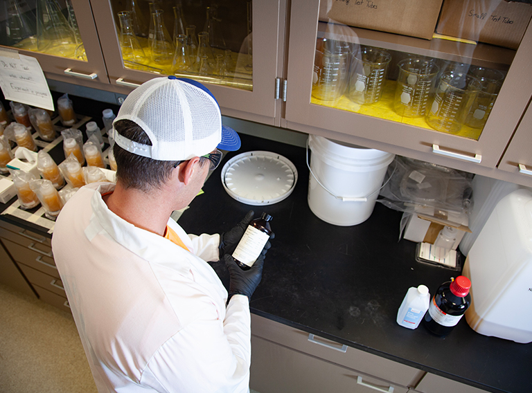 customized waste management worker wearing hat, safety glasses, and white coat