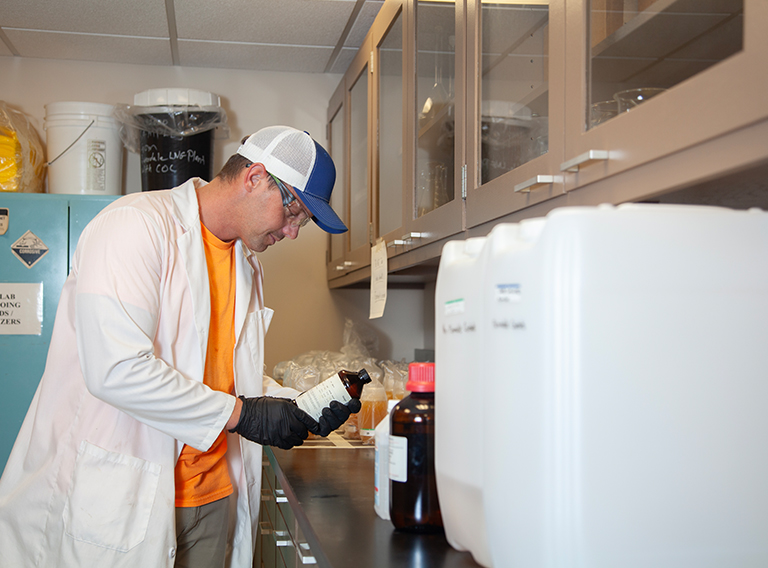 customized waste management worker wearing hat, safety glasses, and white coat