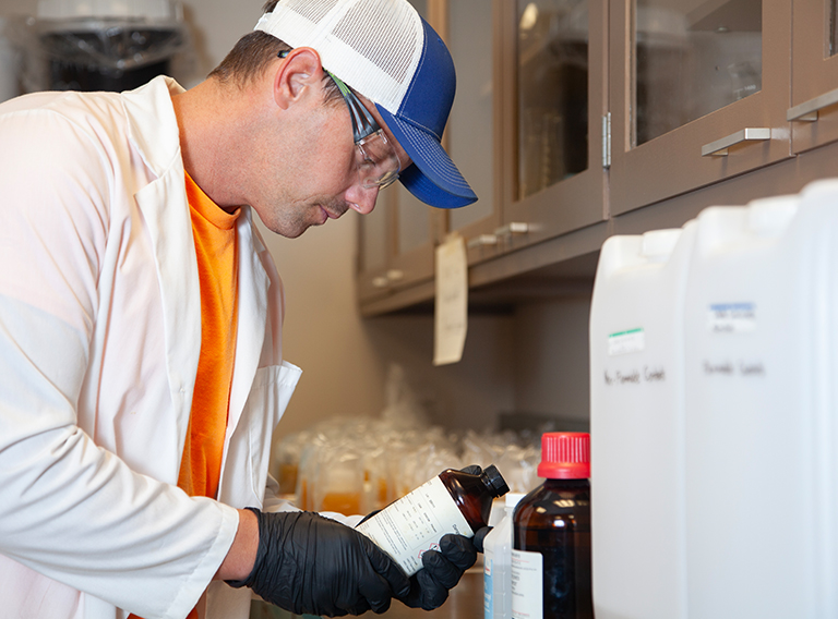 customized waste management worker wearing hat, safety glasses, and white coat