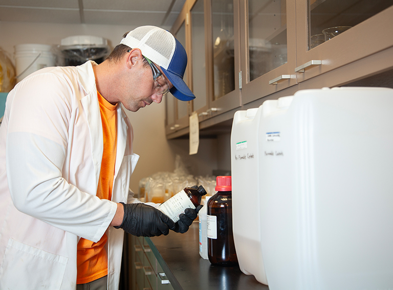 customized waste management worker wearing hat, safety glasses, and white coat