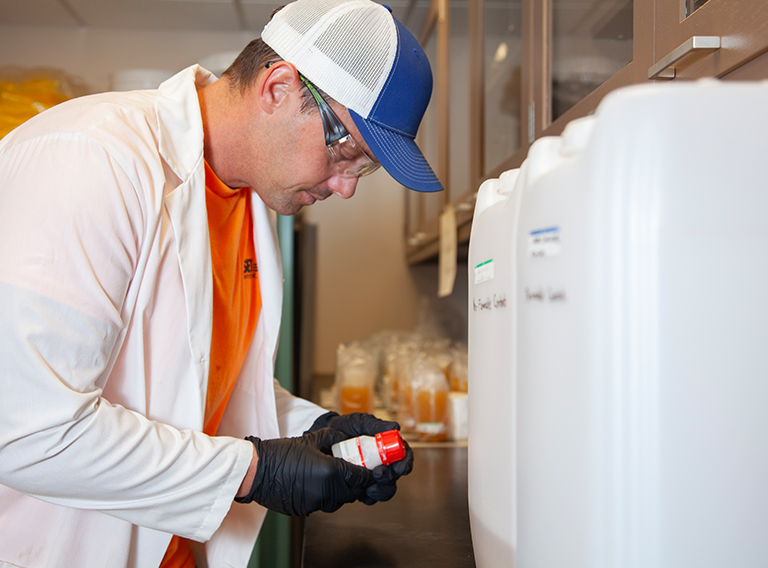 customized waste management worker wearing hat, safety glasses, and white coat