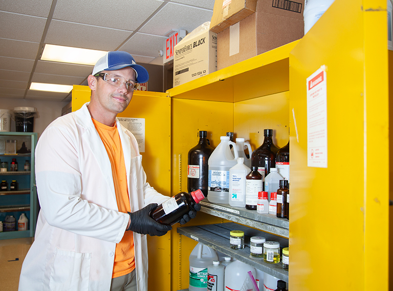 customized waste management worker wearing hat, safety glasses, and white coat