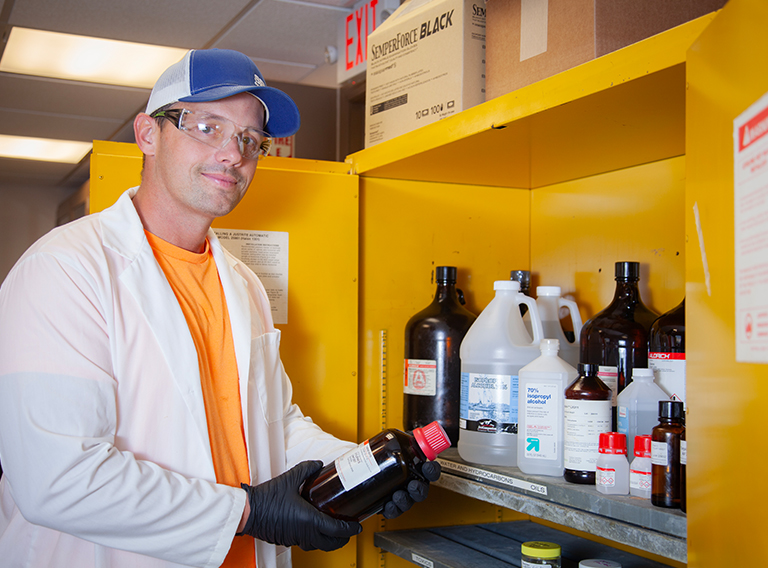 customized waste management worker wearing hat, safety glasses, and white coat