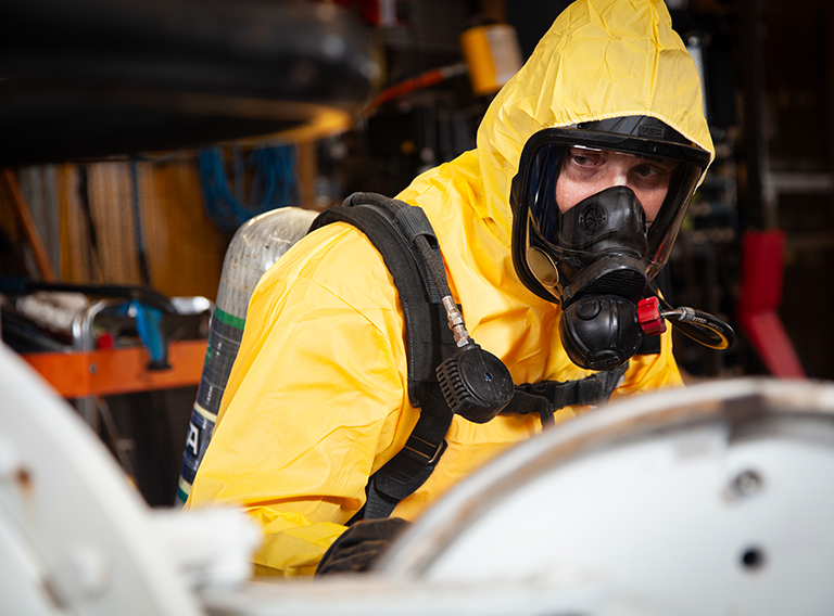 compressed gas recycle disposal worker geared up in yellow suit with oxygen mask