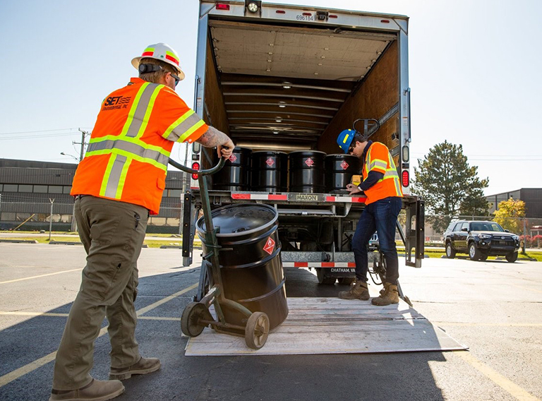 SET Environmental workers loading a customized waste management truck