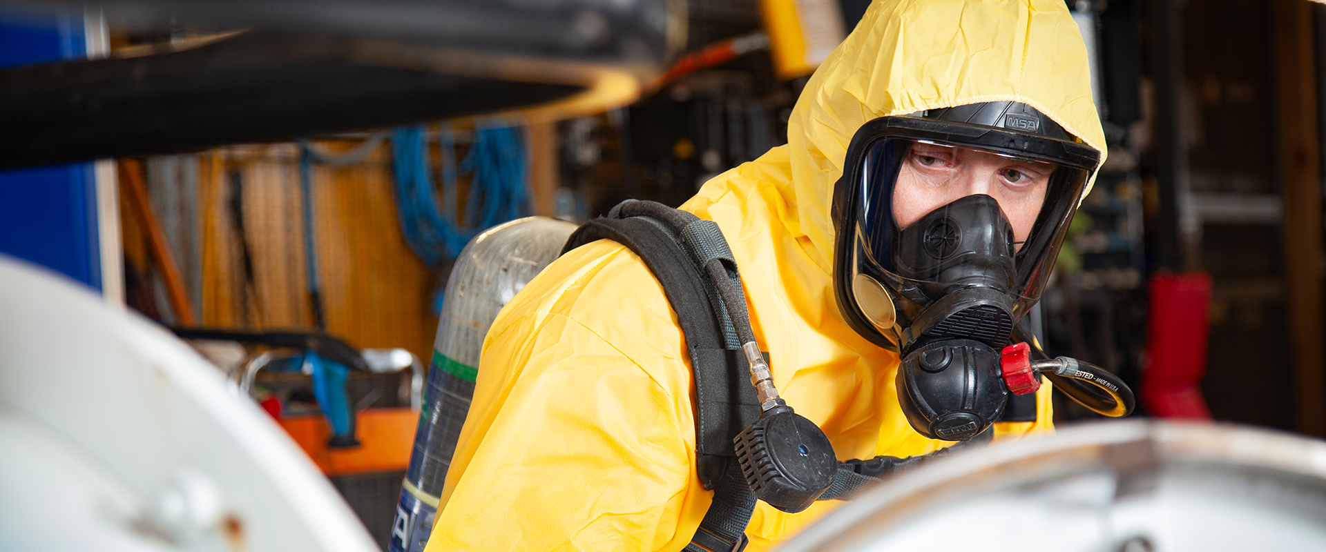 compressed gas recycle disposal worker geared up in yellow suit with oxygen mask